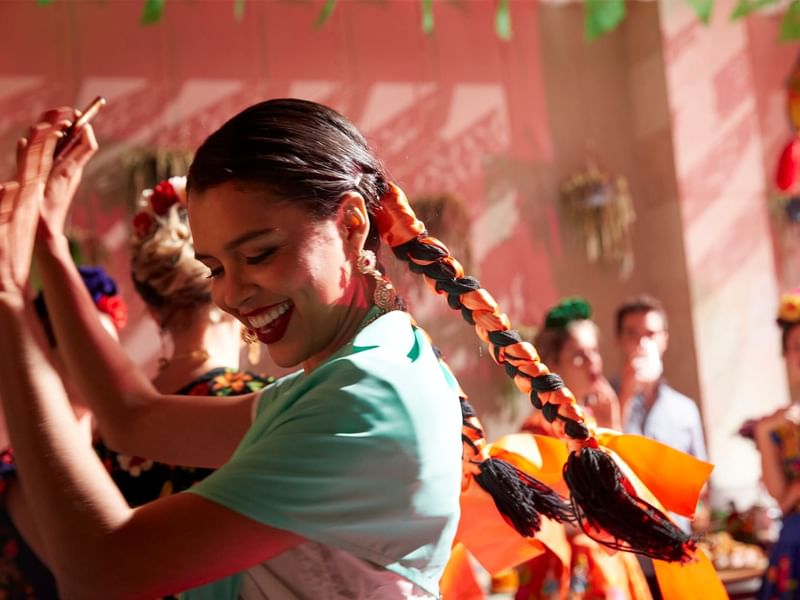 Woman energetically dancing with a crowd at Fiesta Americana