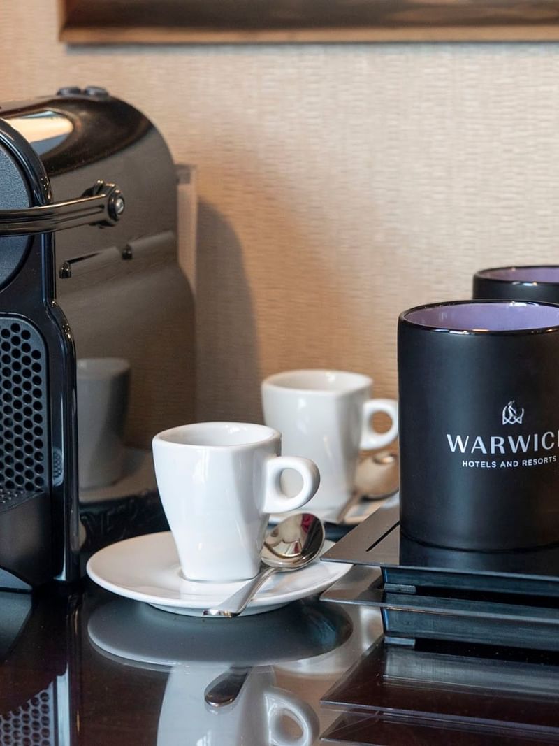 Nespresso machine by black branded mugs and white espresso cups in Superior Room at Warwick Paris Champs Elysées