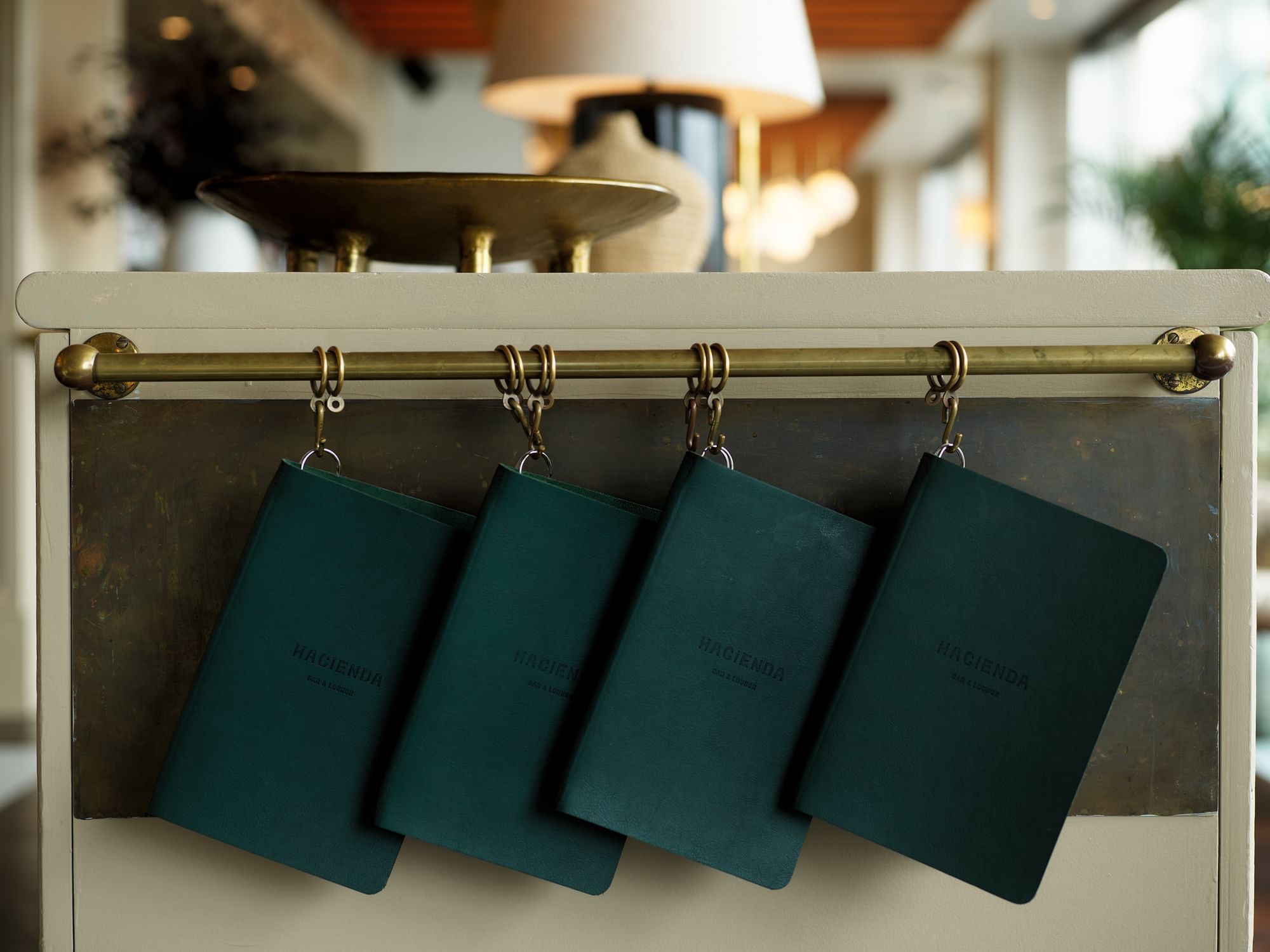 Close-up of leather-bound menus hanging from a brass rail at Pullman Quay Grand Sydney