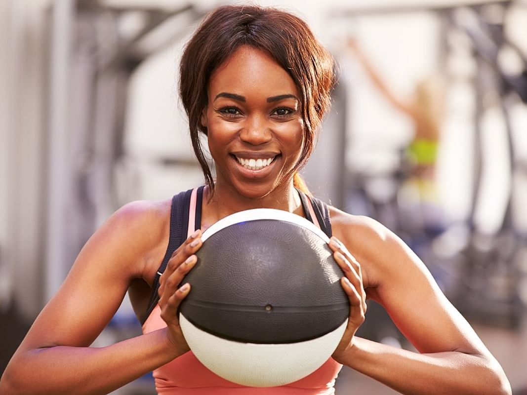 Cheerful woman holds a medicine ball in the well-equipped Fitness Center at Paramount Hotel Portland