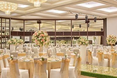 A magnificent ballroom at Goodwood Park Hotel set up for a banquet with lavish floral arrangements and gold and white decor