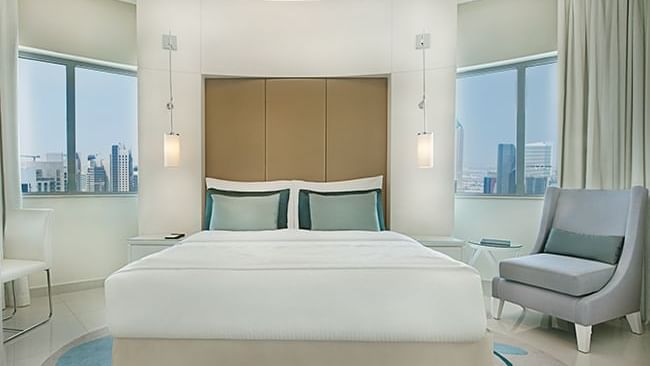Comfy bed, chairs and city view in Deluxe Room at DAMAC Maison Dubai Mall Street