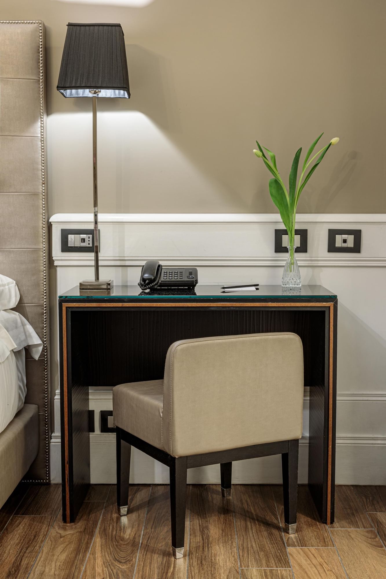 Modern desk with phone, sleek lamp, vase, and minimalist chair in the Classic Room at The Independent Suites
