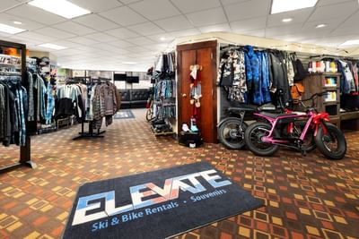 Store with clothing, helmets, bikes, and a rug saying Elevate Ski & Bike Rentals Souvenirs at Elevation Resort Spa