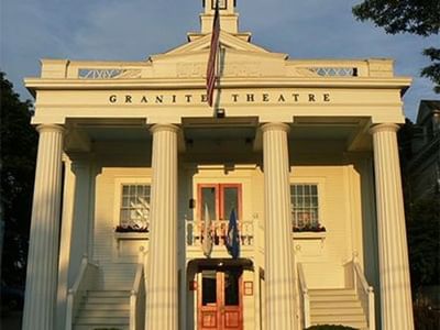 Front view of Granite Theatre, featuring grand columns and red double doors near Breezeway Boutique Hotel