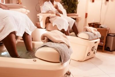Relaxing guests receiving a soothing pedicure treatment in plush white spa chairs at Sugar Cane Club Hotel & Spa