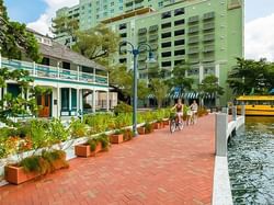 bikers on brick path next to river and water taxi