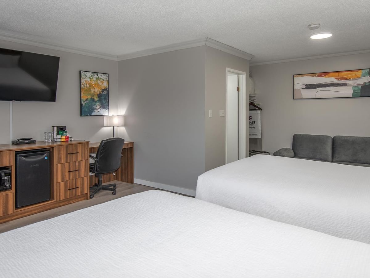 Room with two queen beds, desk, chair, TV, and mini-fridge.