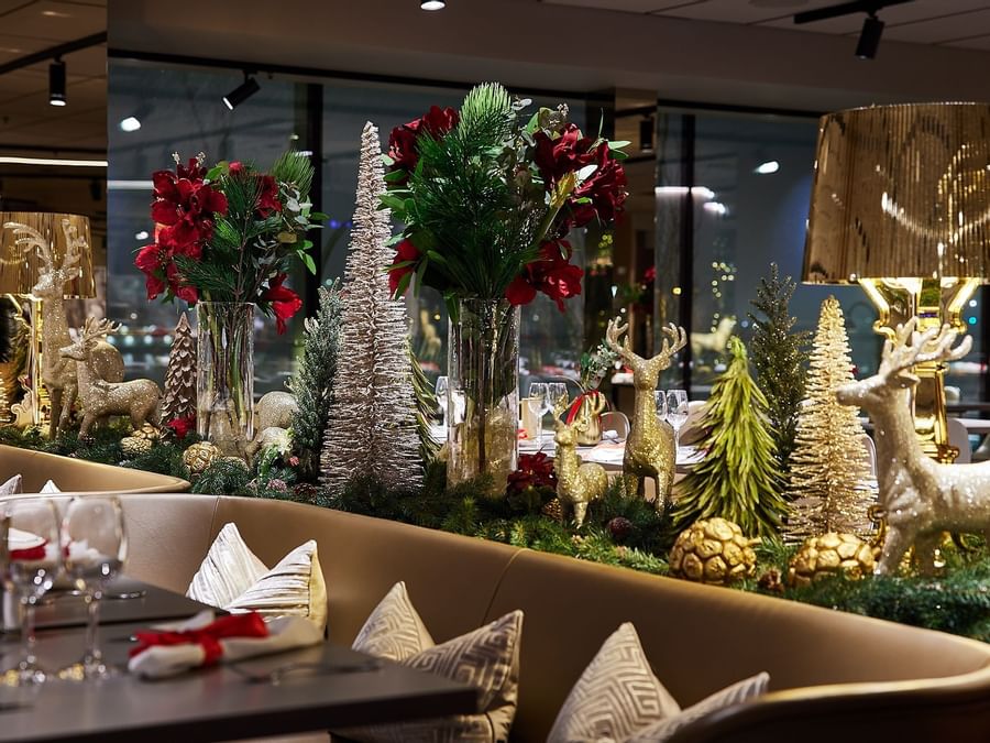 En elegant dekorerad restaurang med juldekorationer, blommor, och belysta bord och stolar.