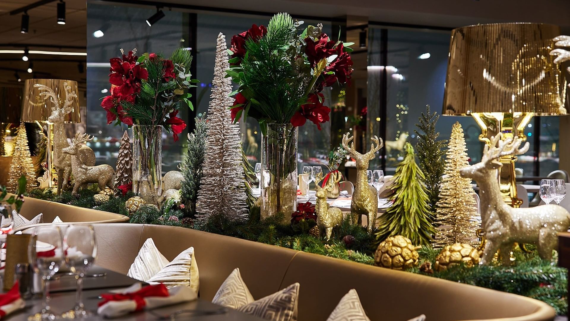 En elegant dekorerad restaurang med juldekorationer, blommor, och belysta bord och stolar.