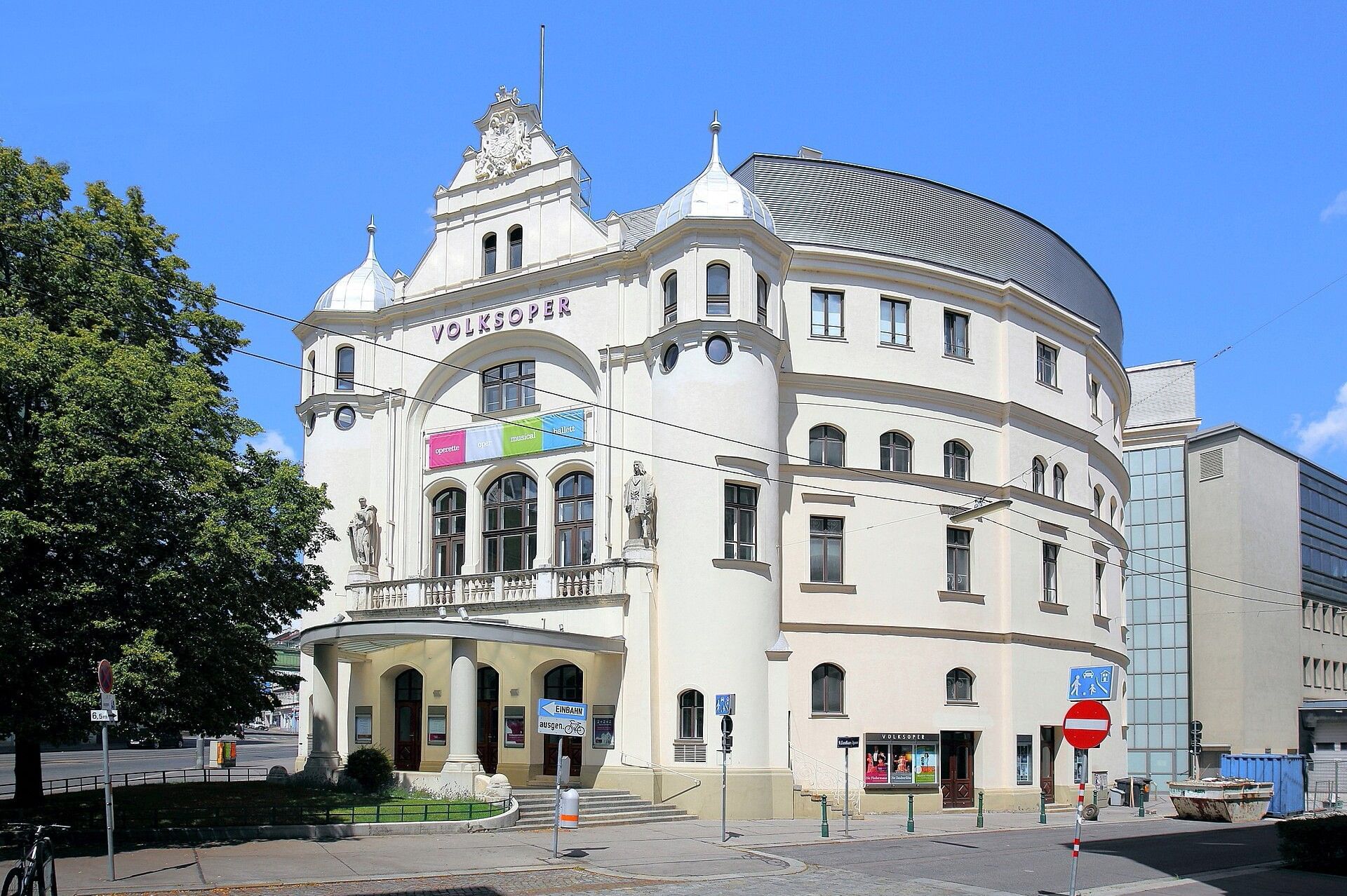 Exterior view of Vienna’s Volksoper featuring its historic theatre facade and distinctive curved architecture under a clear blue sky