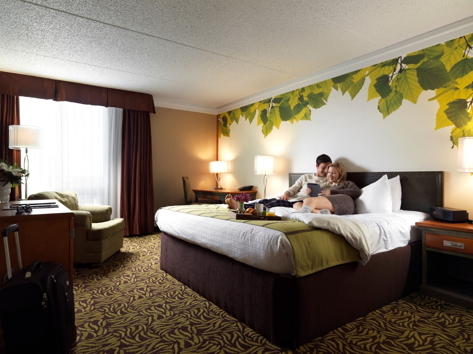 A couple having breakfast on bed in a hotel room at Varscona Hotel on Whyte