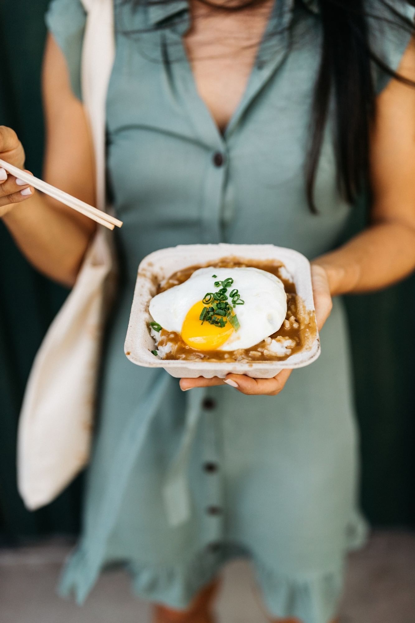 A lady holding an egg & rice dish outdoors near Waikiki Resort Hotel