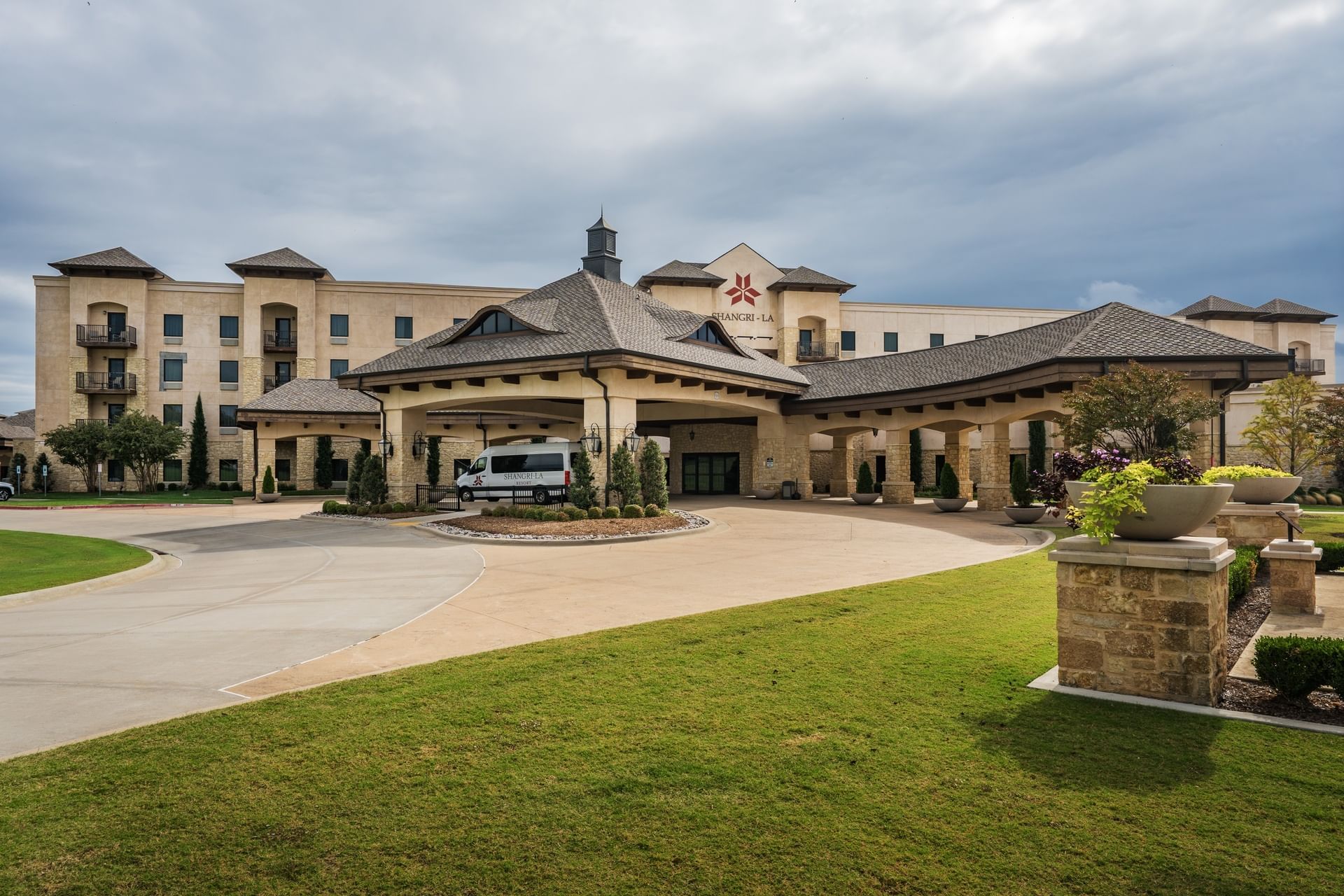 The grand porte-cochere entrance of Shangri-La Resort and Golf Club under a cloudy afternoon sky