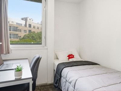 Clean single room with desk, laptop, and bed at Student Living Auckland Anzac.
