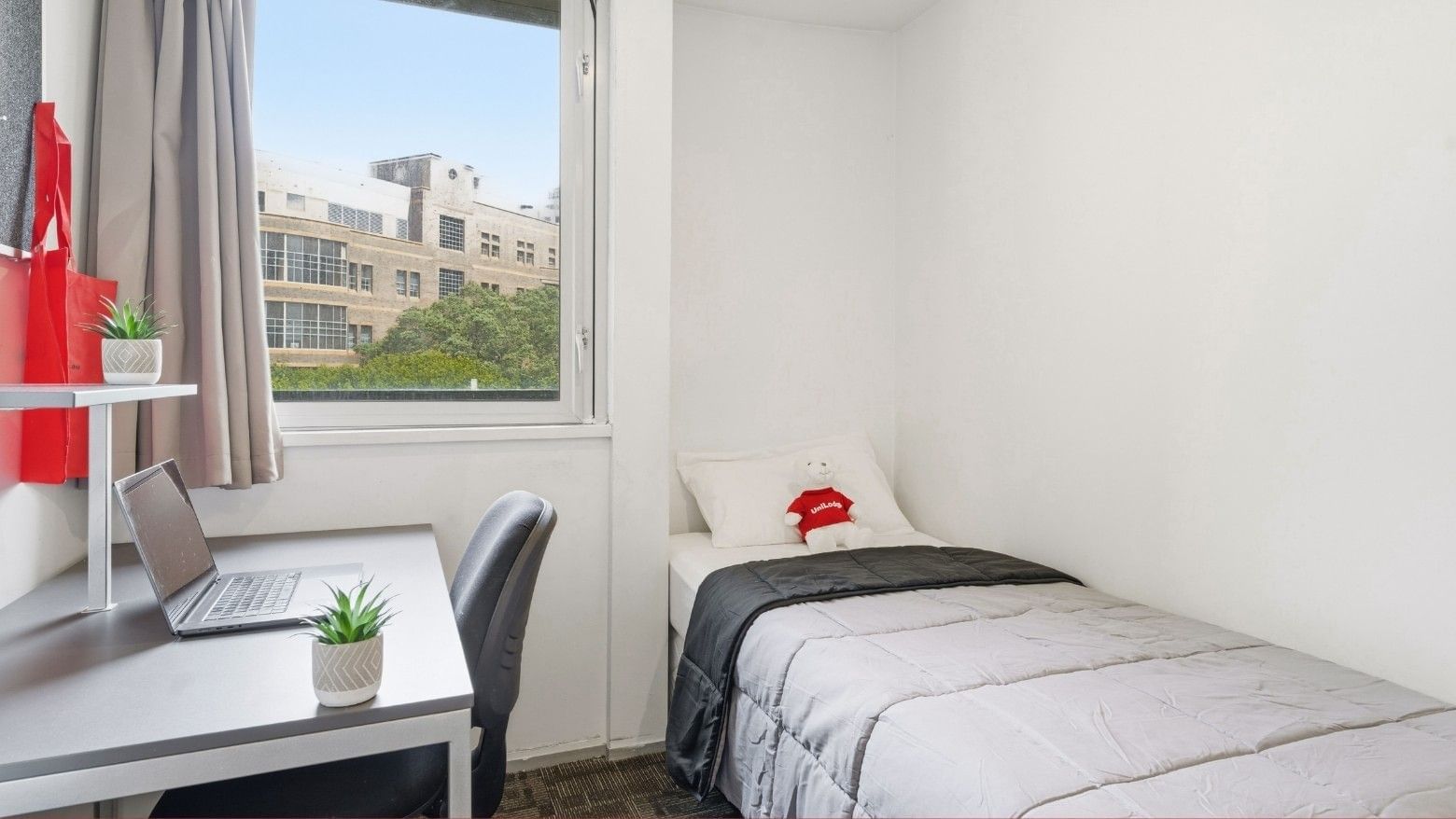 Clean single room with desk, laptop, and bed at Student Living Auckland Anzac.