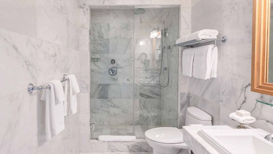 Bathroom featuring a glass-enclosed shower, modern toilet & towels in Deluxe King Suite at El Prado Hotel