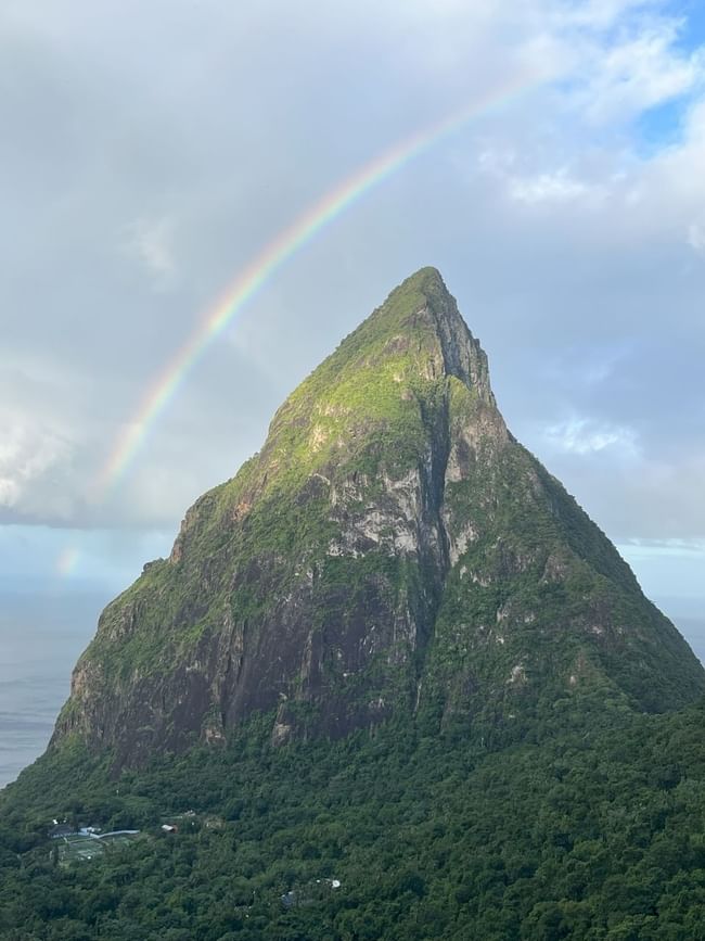 Stunning view of the Pitons in St Lucia at sunset, with lush greenery and a serene ocean in the background