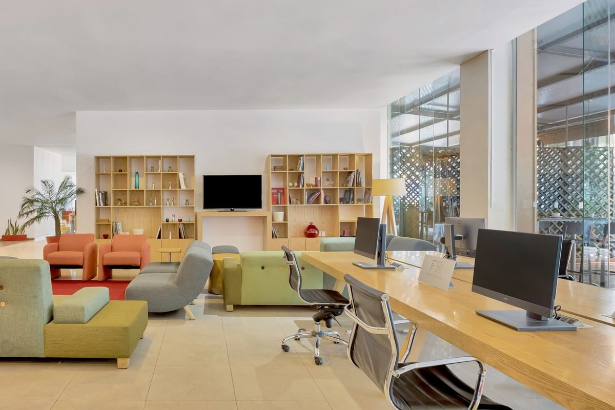 Centro de negocios vibrante con asientos cómodos y escritorio largo compartido en Fiesta Inn