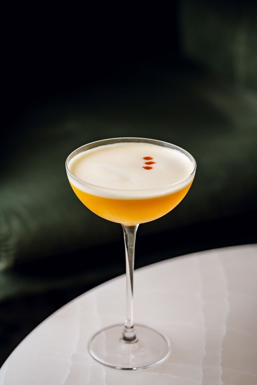 Close-up of frothy yellow cocktail with garnish in glass on table at Capital Bar in Tom Brown at The Capital