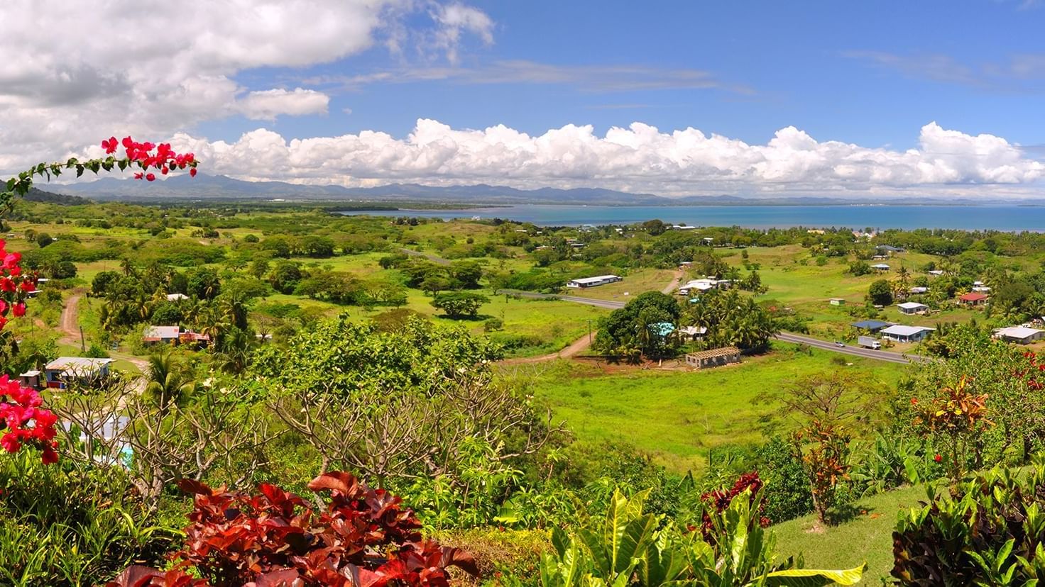 Vast green landscape with homes, a road, and a bay, featuring Nadi Fiji nature near Warwick Hotels and Resorts
