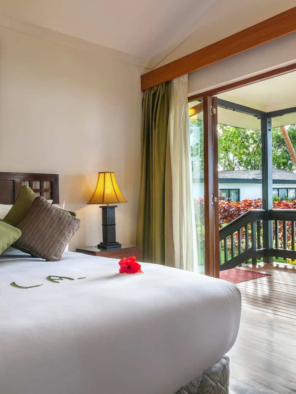 King bed by glass doors under a vaulted ceiling near a private balcony in One-Bedroom Villa at The Naviti Resort - Fiji