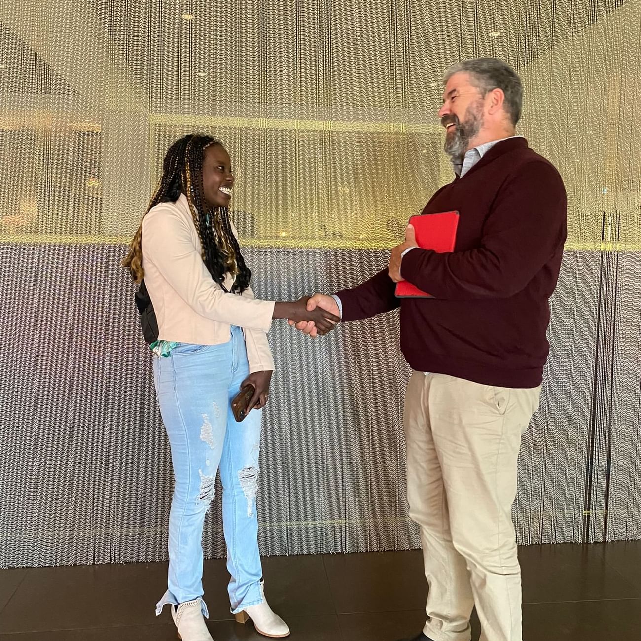 A man and a woman in jeans shake hands at Sofitel Brisbane Central