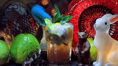 A refreshing cocktail garnished with mint and citrus, surrounded by playful decorations and vibrant fruit at The Gaythering