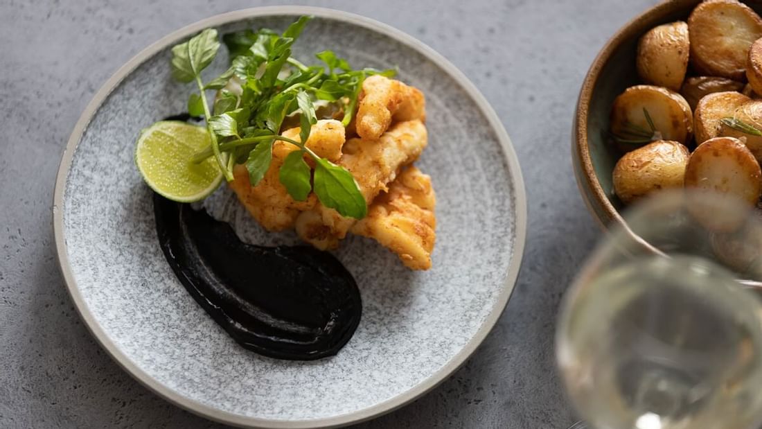 Fried calamari with lime, dark sauce, and greens served in The Marke Kitchen at Novotel Sydney International Airport