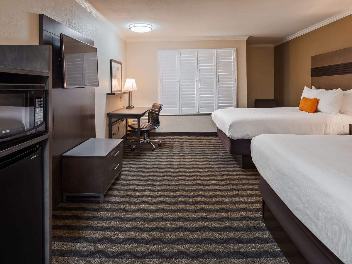 two beds and a wall mounted tv in a hotel room