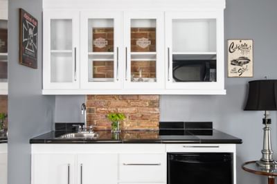 Kitchenette with black counter-top, appliances & exposed brick wall in Queen Premiere Easy Rider at Retro Suites Hotel