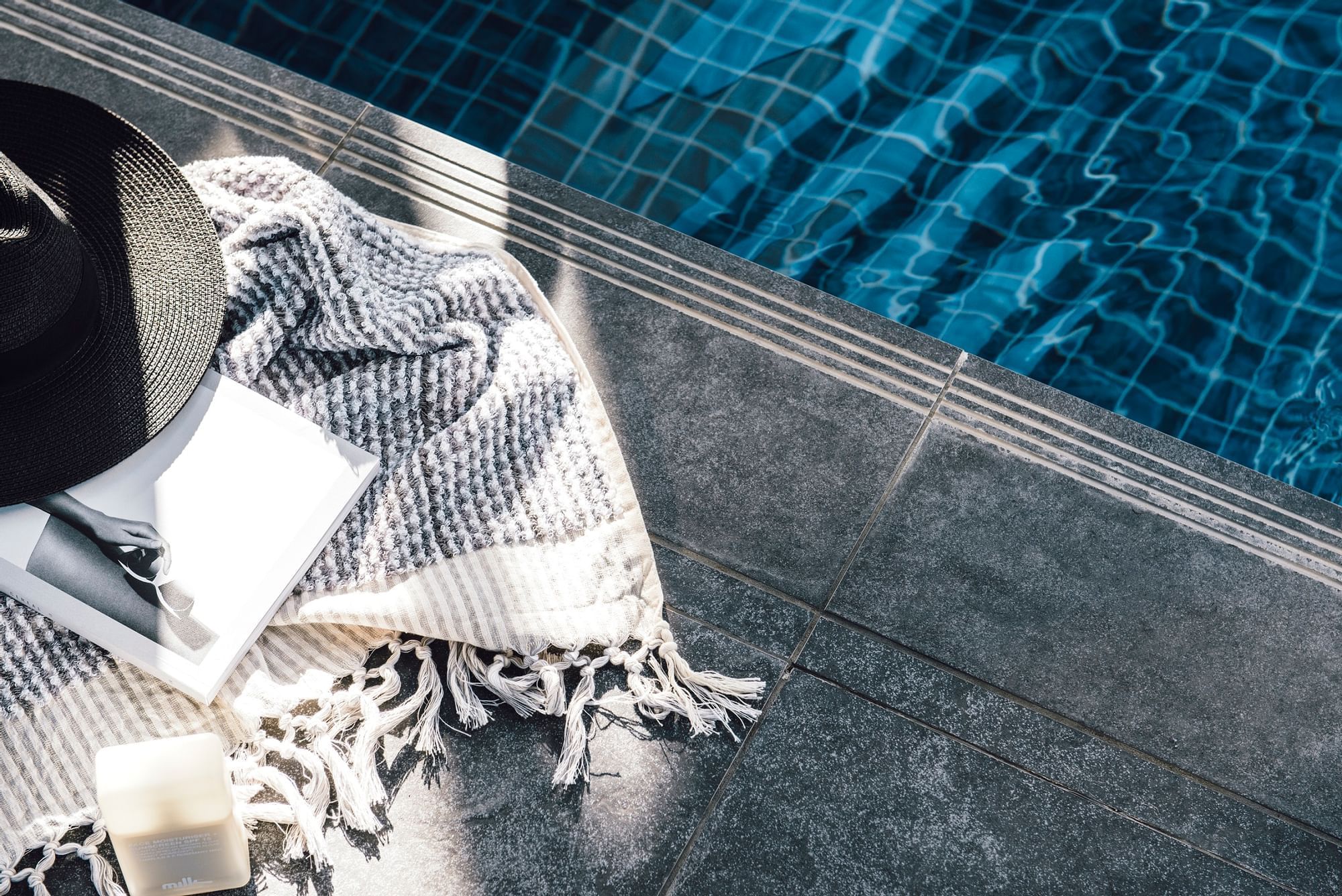 Close-up of blanket, book & hat by the pool at Como Melbourne
