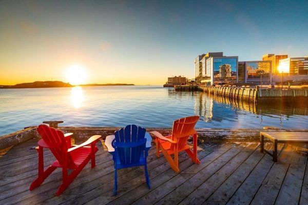 Halifax boardwalk with red, blue and orange deck chairs and the sun setting in the back