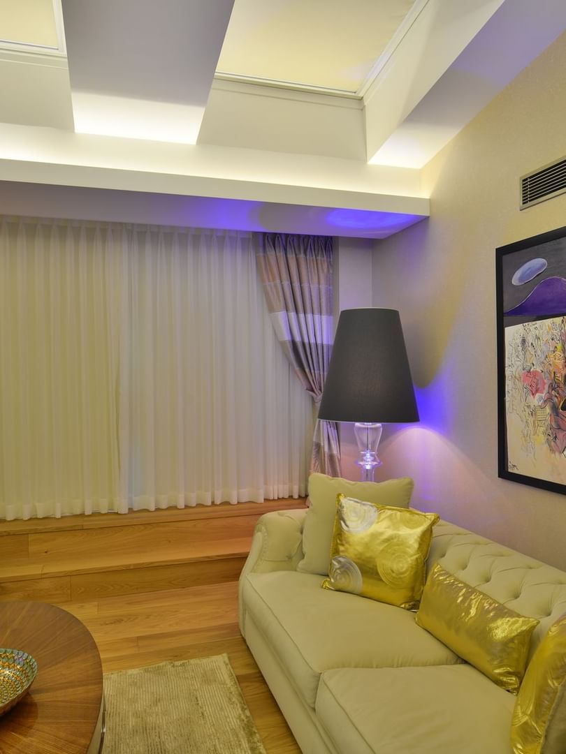Beige sofa and gold pillows by a coffee table under a large art piece in Warwick Suite with Terrace at Warwick Ankara
