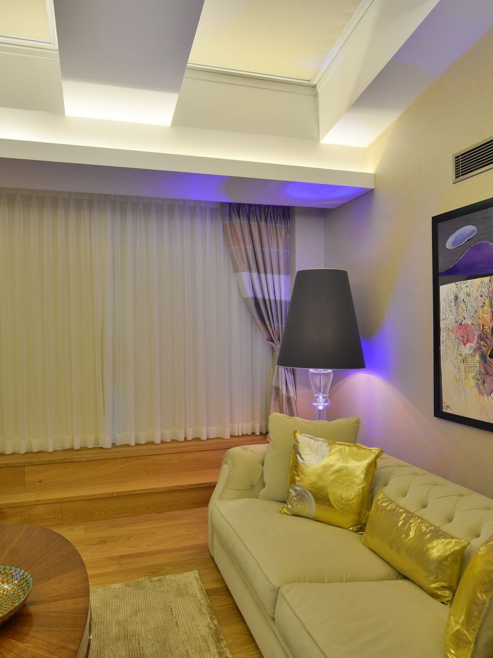 Beige sofa and gold pillows by a coffee table under a large art piece in Warwick Suite with Terrace at Warwick Ankara
