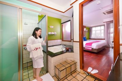 Woman in spa robe in glass shower of delux water chalet bathroom connected to a bedroom – Lexis Port Dickson