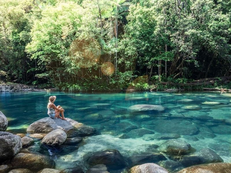 Lady sitting on a rock overlooking the river in Mossman Gorge near Pullman Port Douglas