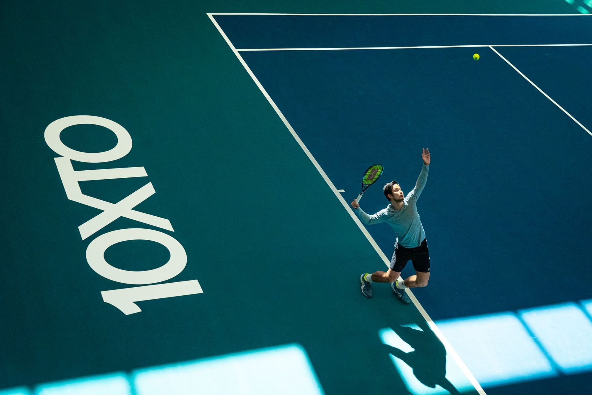 Tennis player reaching for a ball on an indoor court in 10XTO Athletic Club at Hotel X Toronto