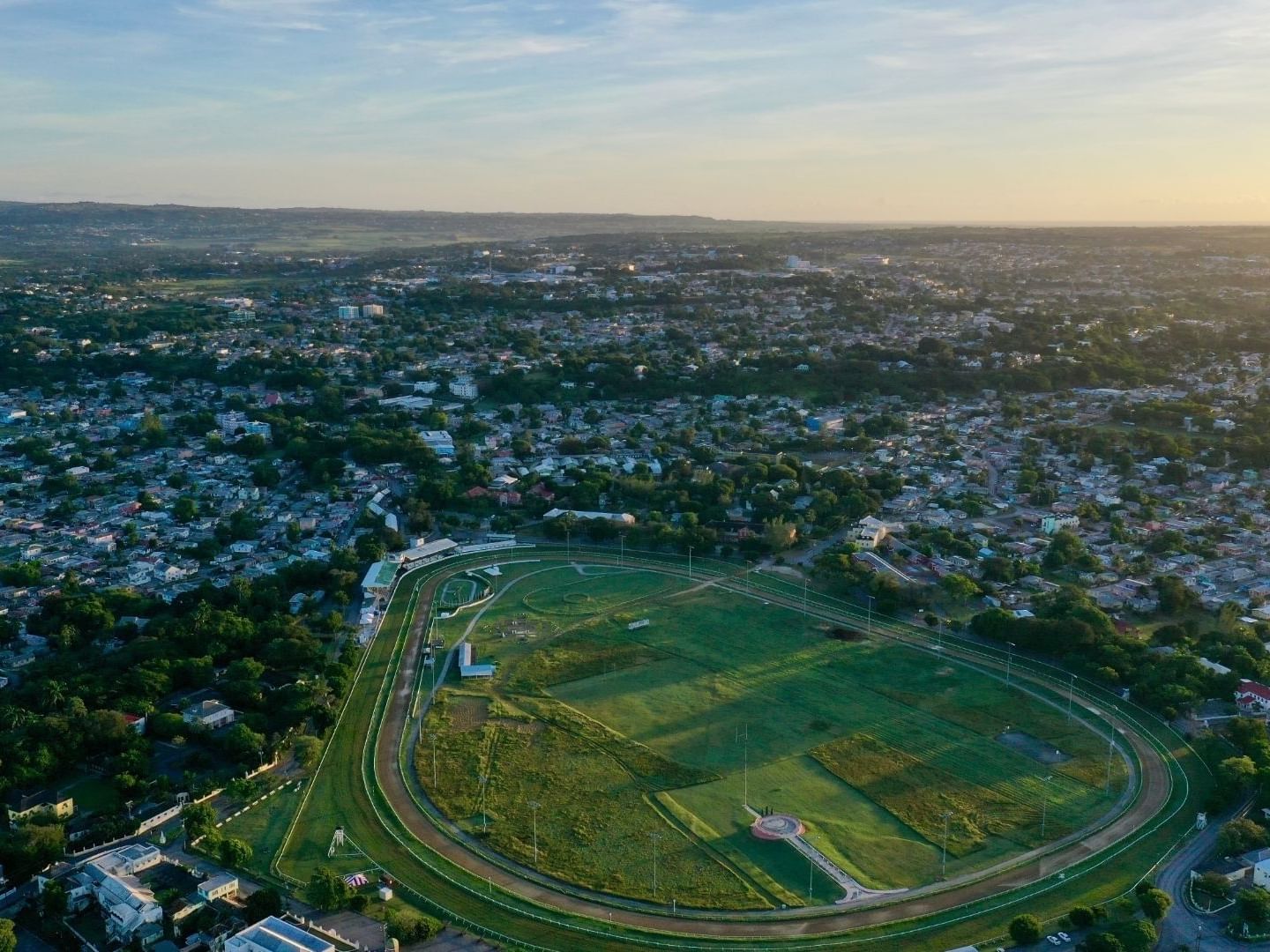 Aerial view of a large green park with a racetrack surrounded by urban buildings.