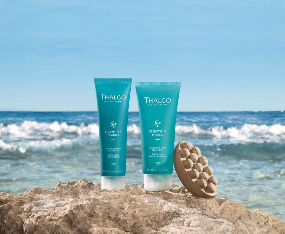 Two turquoise Thalgo skincare tubes on a rock by the ocean near The Saujana Hotel Kuala Lumpur
