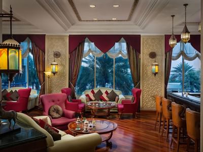 Sofas with red curtains & pillows at a café at Ajman Hotel