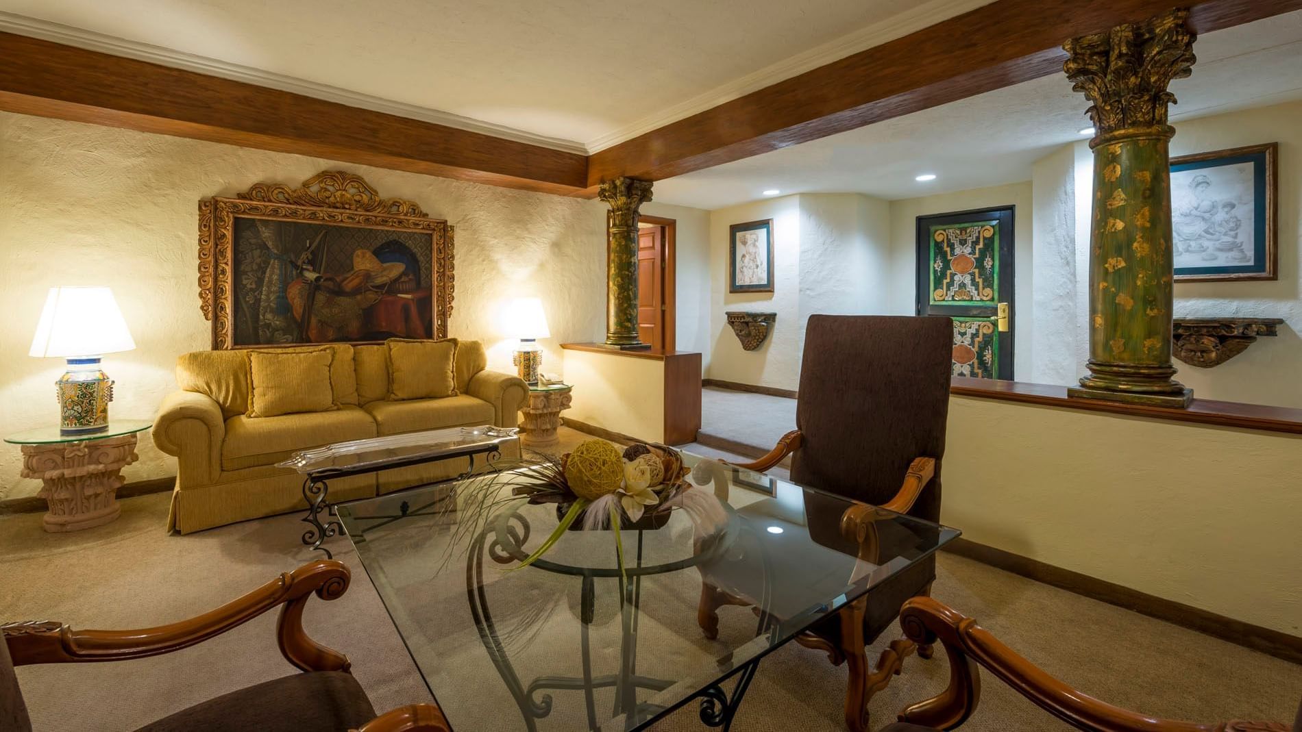 King Aguascalientes Suite with green columns, gold-framed art, and glass tables at Quinta Real Aguascalientes