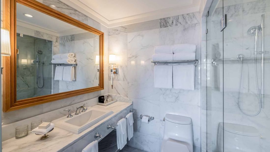 Bathroom with large mirror, spacious vanity, and glass shower in Courtyard Grand Executive King Suite at El Prado Hotel