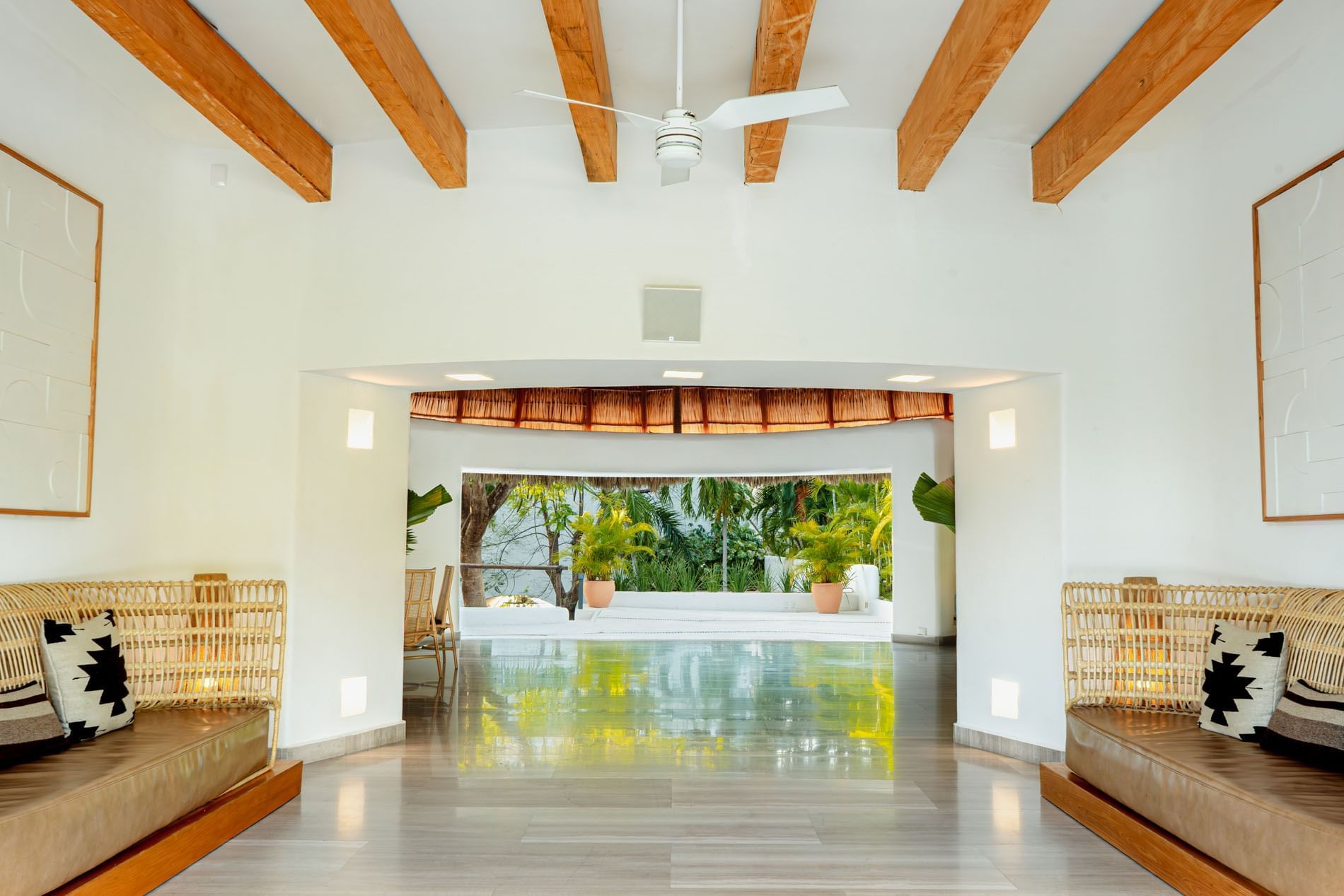 Bright open hallway with wooden ceiling beams and wicker seating at Camino Real Zaashila Huatulco