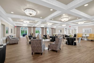 Towpath Ballroom with round tables surrounded by patterned armchairs under chandeliers at Avon Old Farms Hotel