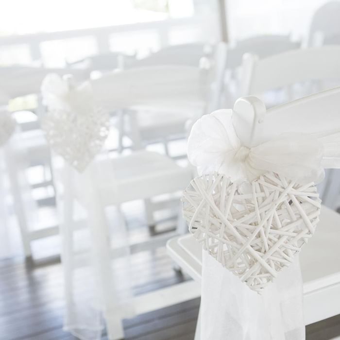 White rustic heart decorations hang from white chairs set in a wedding venue at Mercure Hotel Townsville