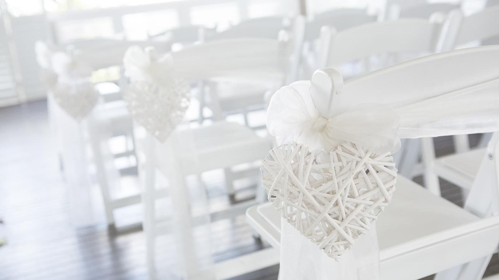 White rustic heart decorations hang from white chairs set in a wedding venue at Mercure Hotel Townsville