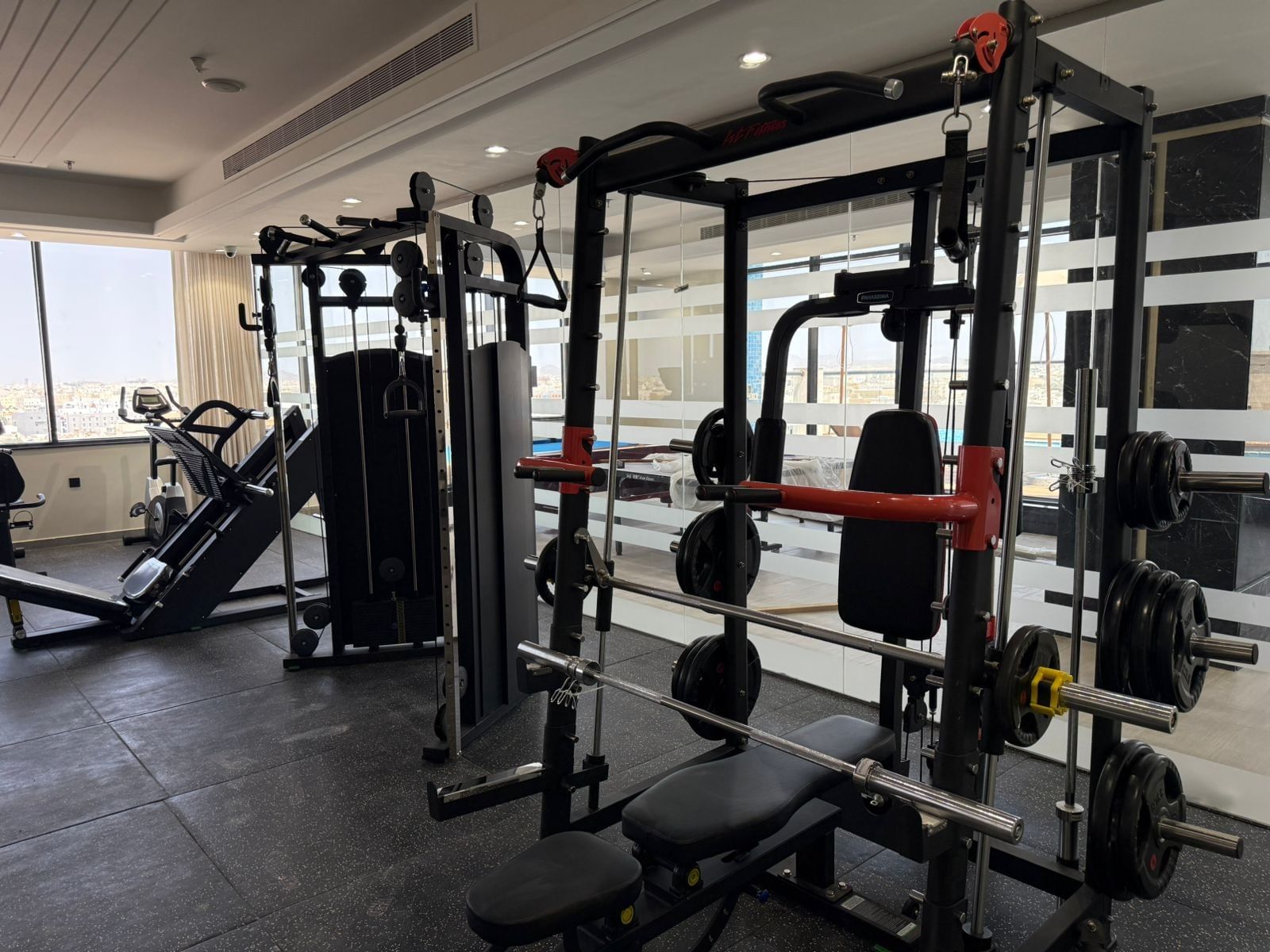 Weight racks by a bench under recessed lights in Gym at Warwick Jeddah Hotel & Spa