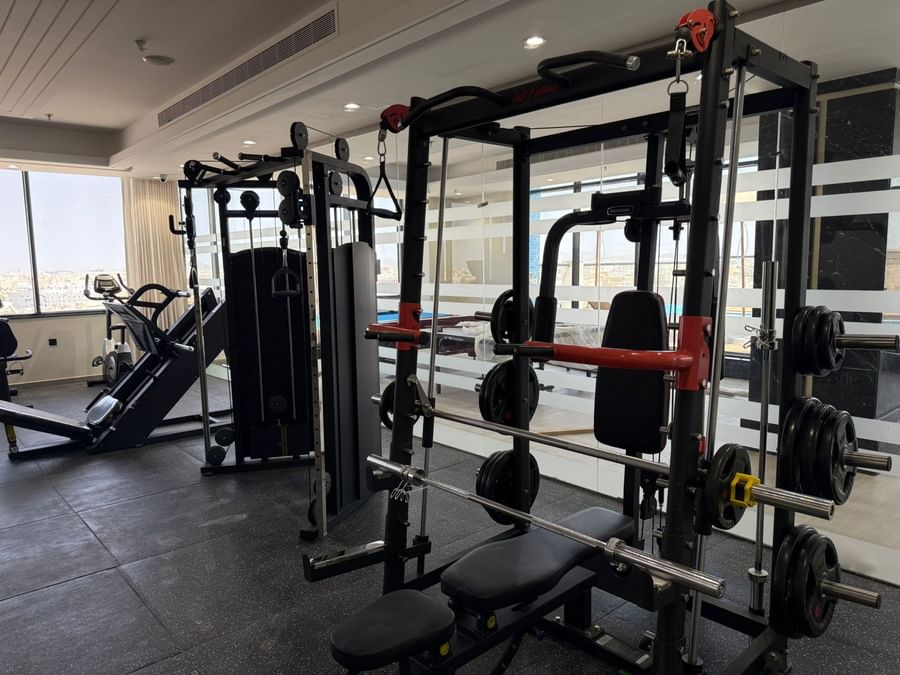 Weight racks by a bench under recessed lights in the gym at Warwick Jeddah Hotel & Spa