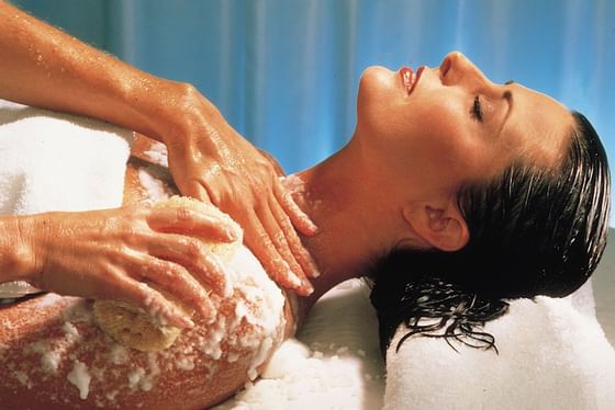Woman receiving body polish massage.